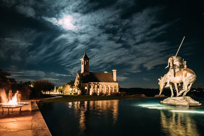 Moonlit clouds over a lit chapel, horse statue, fire pit