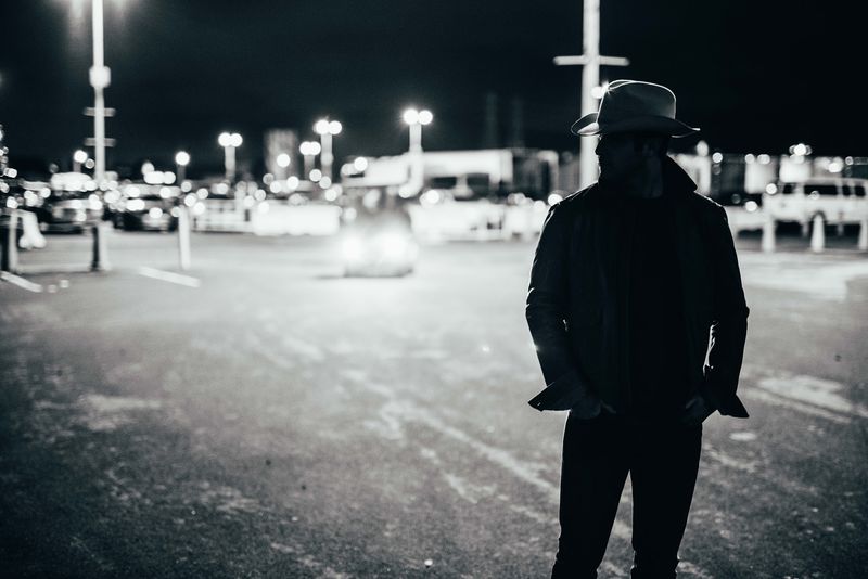 Cowboy-hat silhouette in a night lot full of lights