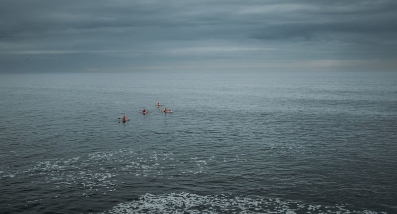 Tiny red swim caps in a vast grey sea