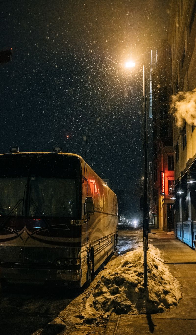 Tour bus under streetlamp, snow falling through the light