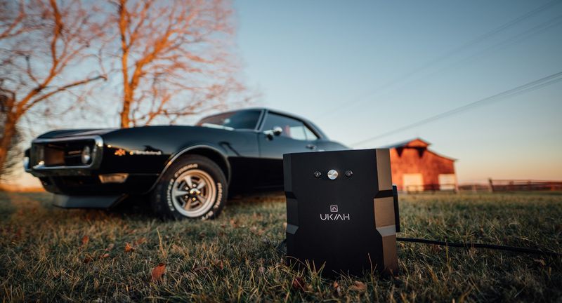 Fire pit beside black Firebird, barn at sunset