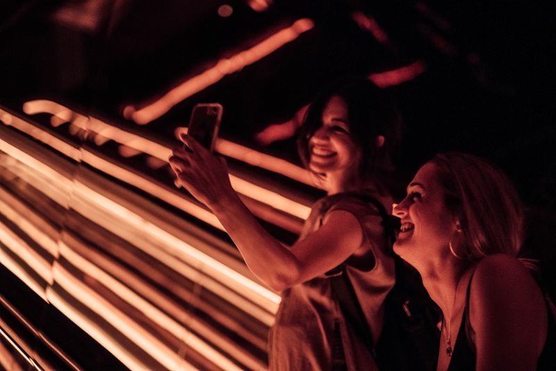 Women taking selfie amid red neon streaks
