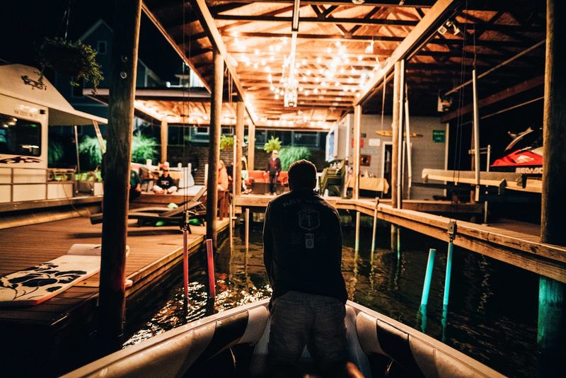 Boat gliding into string-lit boathouse at night