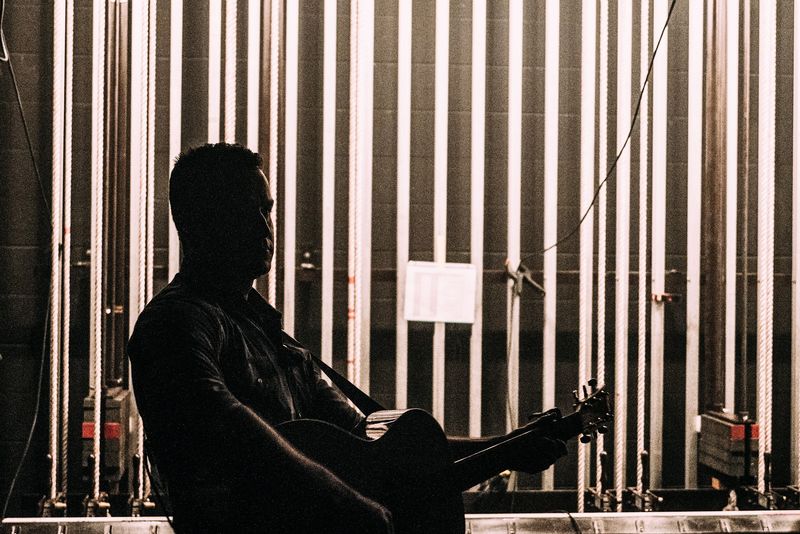 Silhouette with acoustic against vertical rigging lines