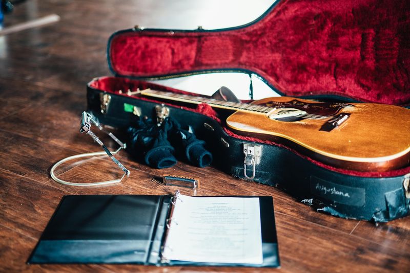 Open red-lined guitar case with lyric binder