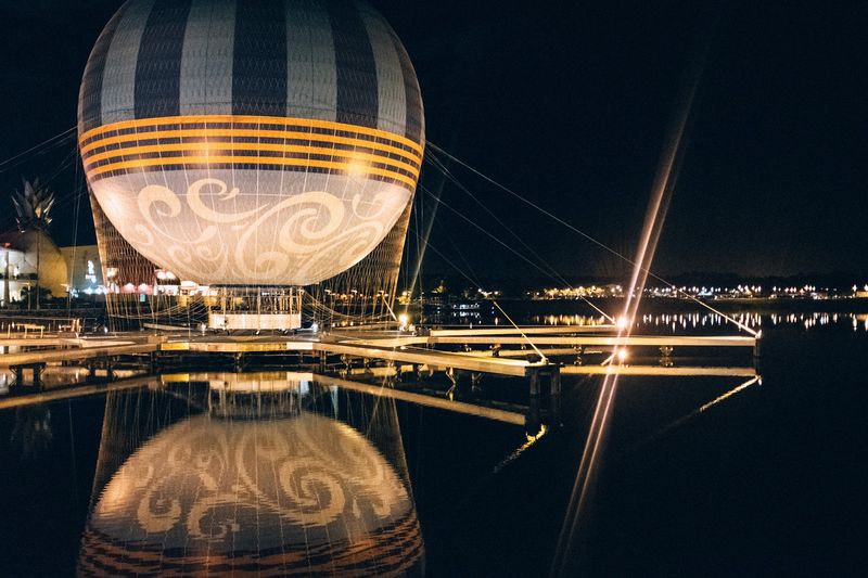 Lit balloon on dock reflected in black water