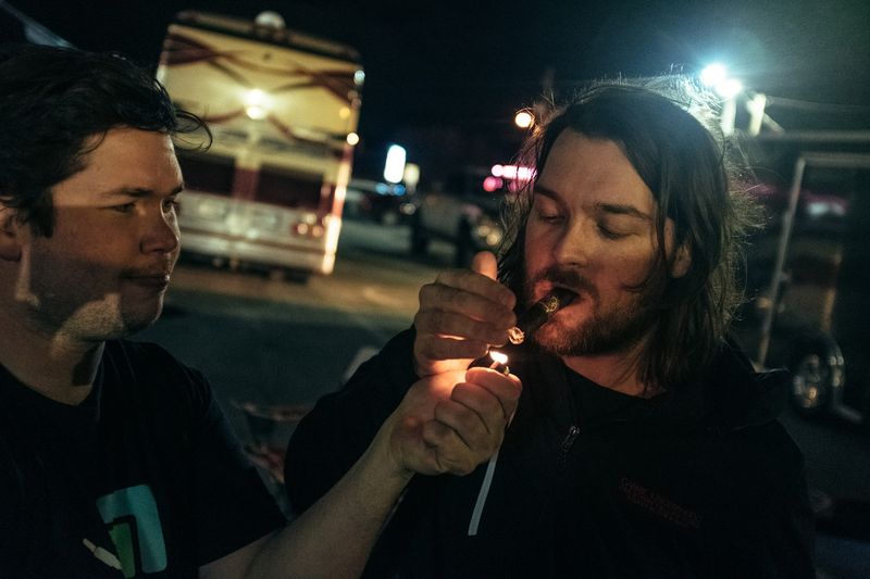 Flame lights cigar between two friends, night