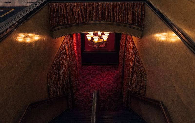 Ornate red staircase descending to chandelier