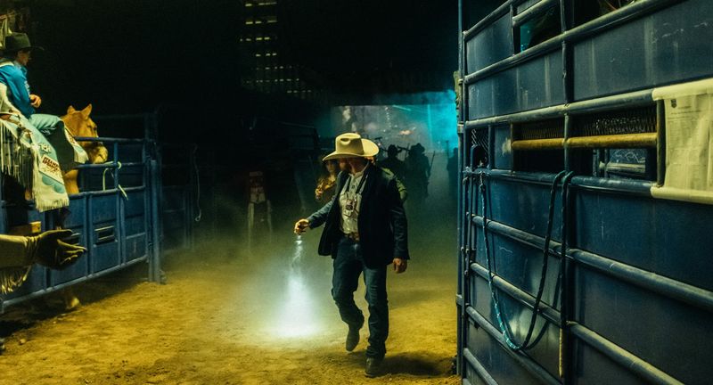 Cowboy with flashlight striding through haze by chutes