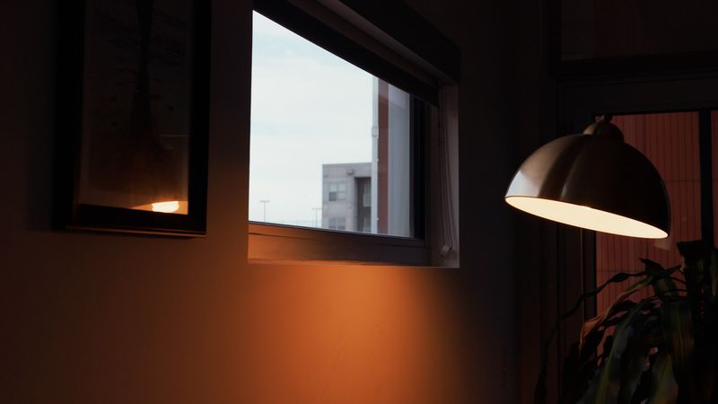 Arc lamp glowing in warm window corner at dusk
