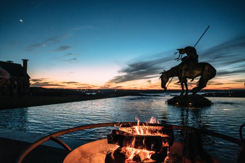Fire pit glows before sculpture and twilight sky