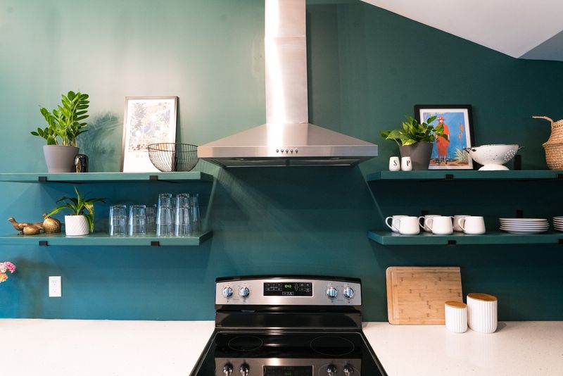Straight-on range hood and floating shelves, teal wall