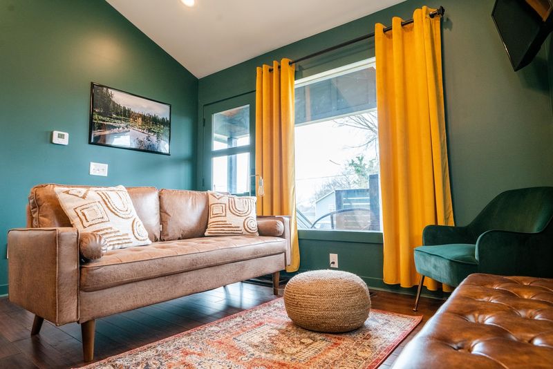 Leather sofa, pouf, mustard curtains in teal room