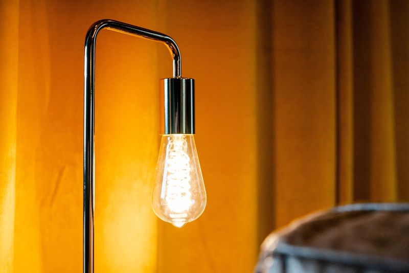 Edison bulb glowing in warm mustard curtain field