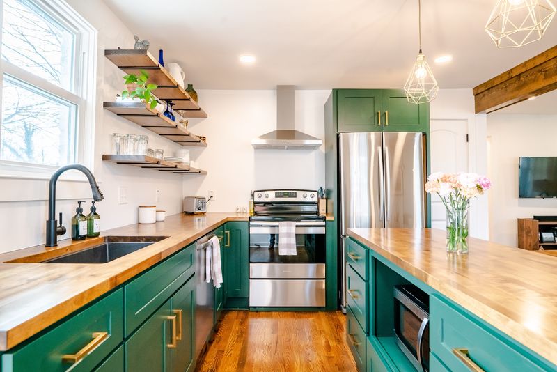 Wide green galley kitchen, butcher block, brass pendants