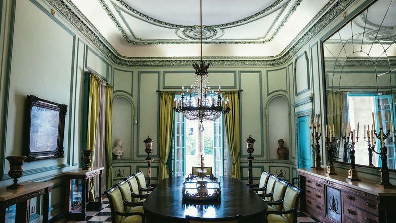 Ornate green colonial dining room with chandelier