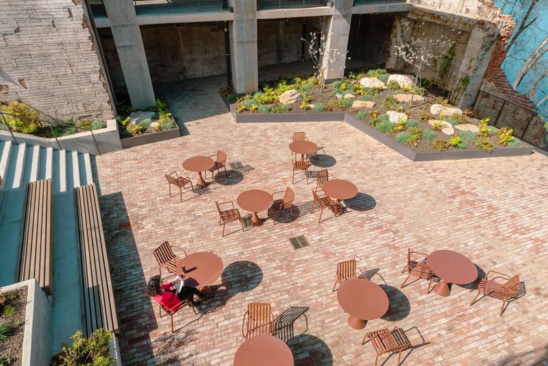 Overhead plaza with round tables casting hard shadows