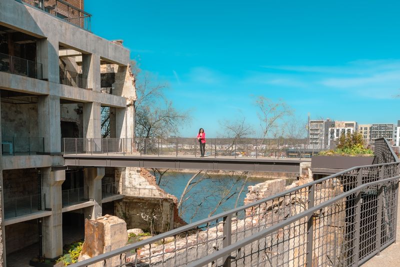 Ruined mill bridge over river with woman in red
