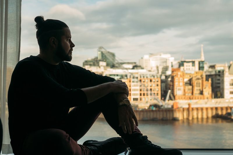 Silhouette on window ledge over Thames skyline