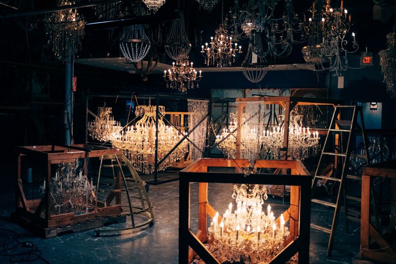 Glowing chandelier in crate amid hanging chandeliers