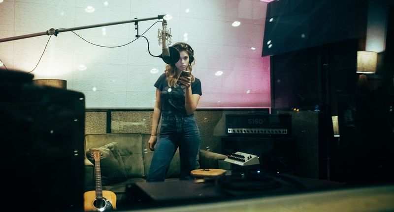 Through glass songwriter sings, teal and pink tones