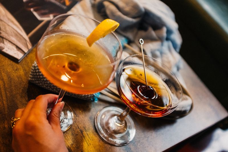 Hand lifts a cherry Manhattan, overhead