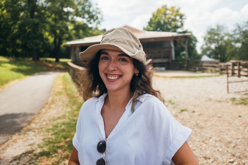 Laughing in a bucket hat on a farm lane, barn behind