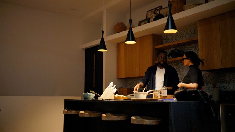 Couple cooking at dark island under pendant lights