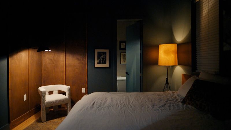Moody bedroom with amber lamp and boucle chair
