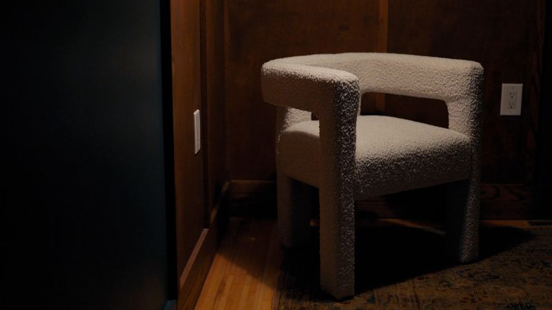 Sculptural boucle chair in dark wood-paneled corner