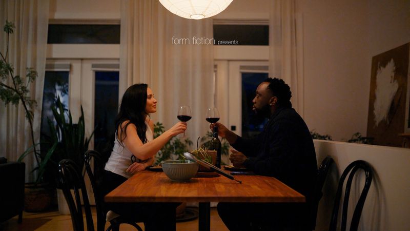 Couple toasting wine at candlelit dining table
