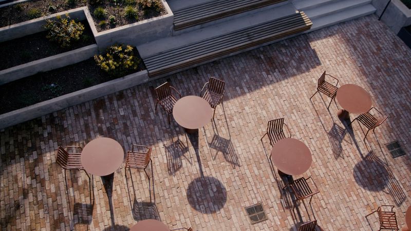 High angle brick plaza, round tables, long shadows