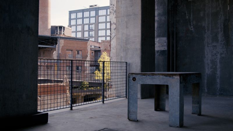 Concrete stool in shadowed bay, city glimpsed beyond
