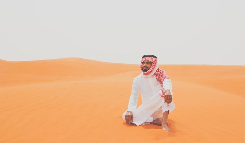 White thobe and red headscarf on an orange dune