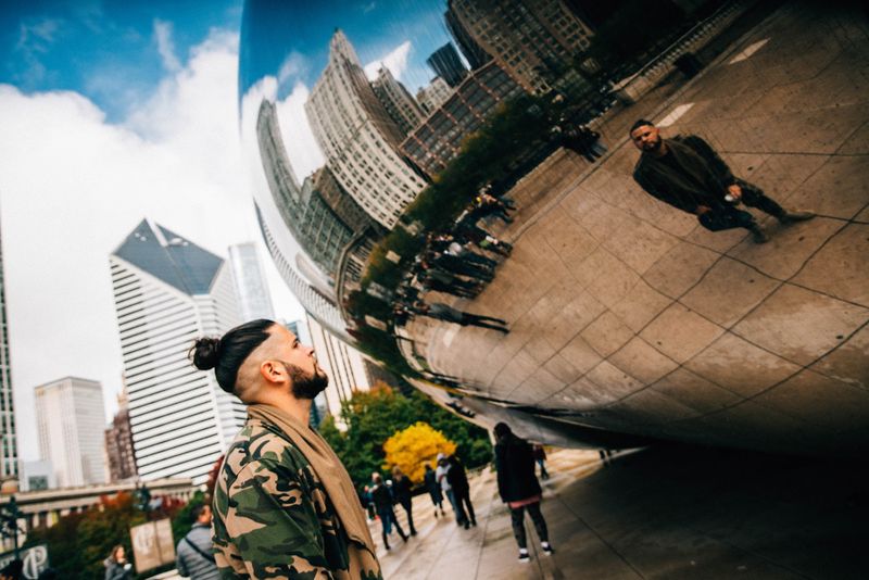 Man looks up while the Bean mirrors him and skyline