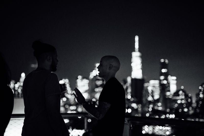 Two silhouettes talk against the glowing Manhattan skyline