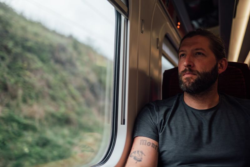 Gazing out a train window, green bank streaking past
