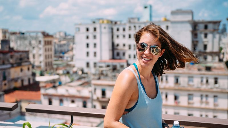 Windblown grin on a rooftop over crumbling pale facades