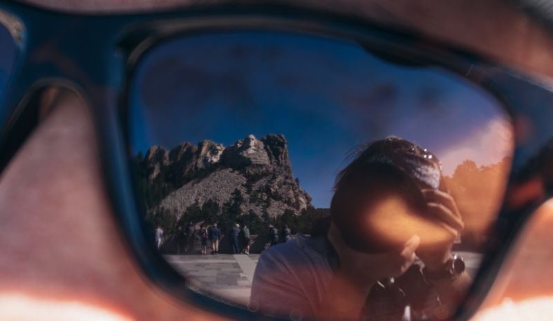 Mount Rushmore and photographer reflected in sunglasses