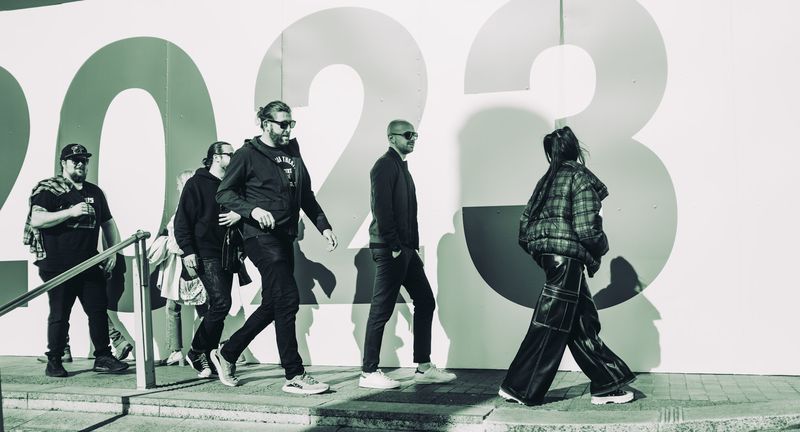 Crew striding past giant 2023 numerals on a white wall