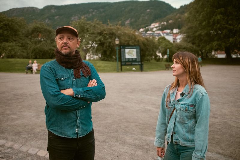 Two people standing apart in a park, her look unanswered