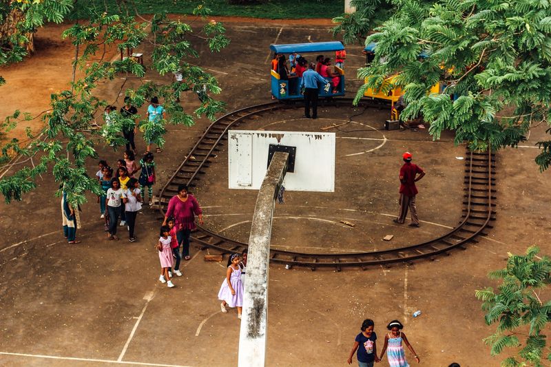 Overhead: basketball court circled by toy train track, kids