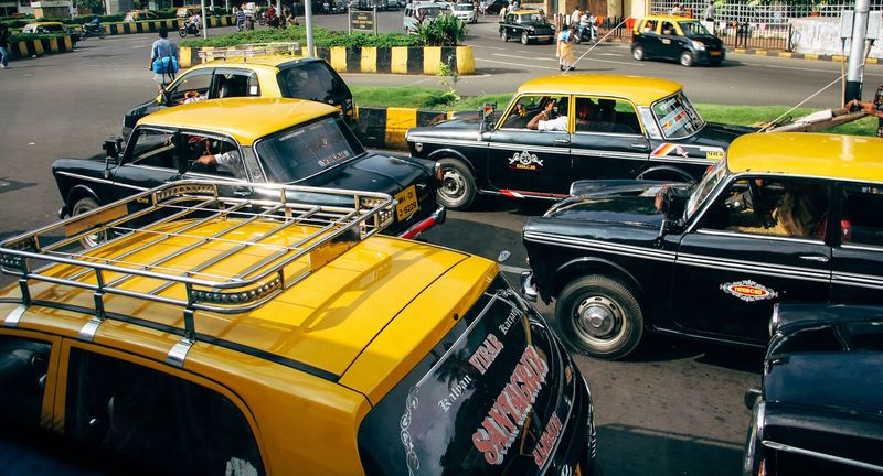 Yellow and black taxis jammed in Mumbai traffic, roof rack