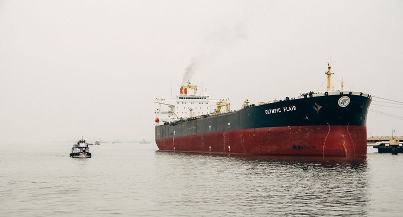 OLYMPIC FLAIR tanker in a misty harbour, a tug in front