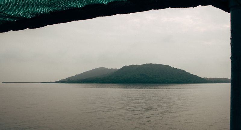 Hazy island seen through a ferry canopy, flat water