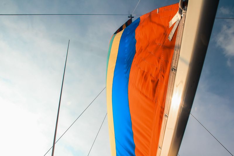 Striped orange and blue sail from below against grey sky