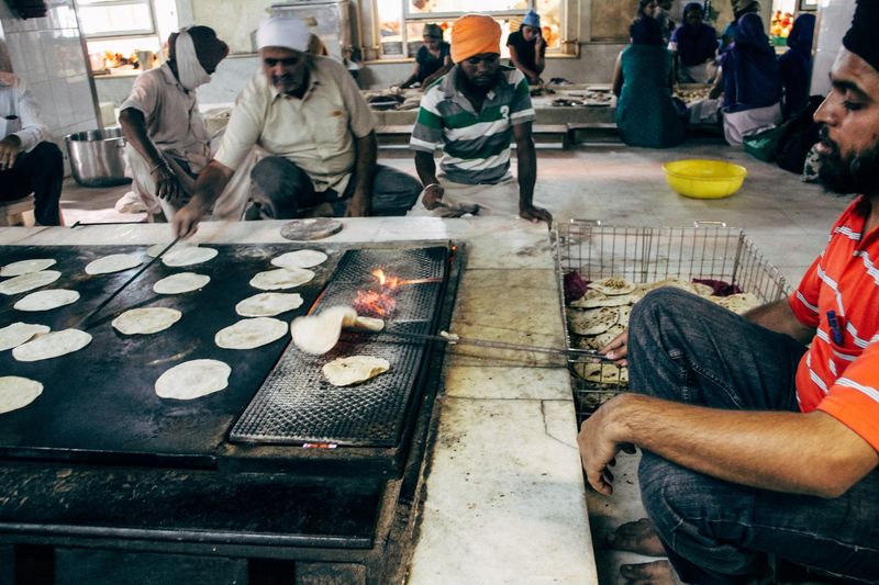 Rows of rotis on the griddle, one flipped over open flame